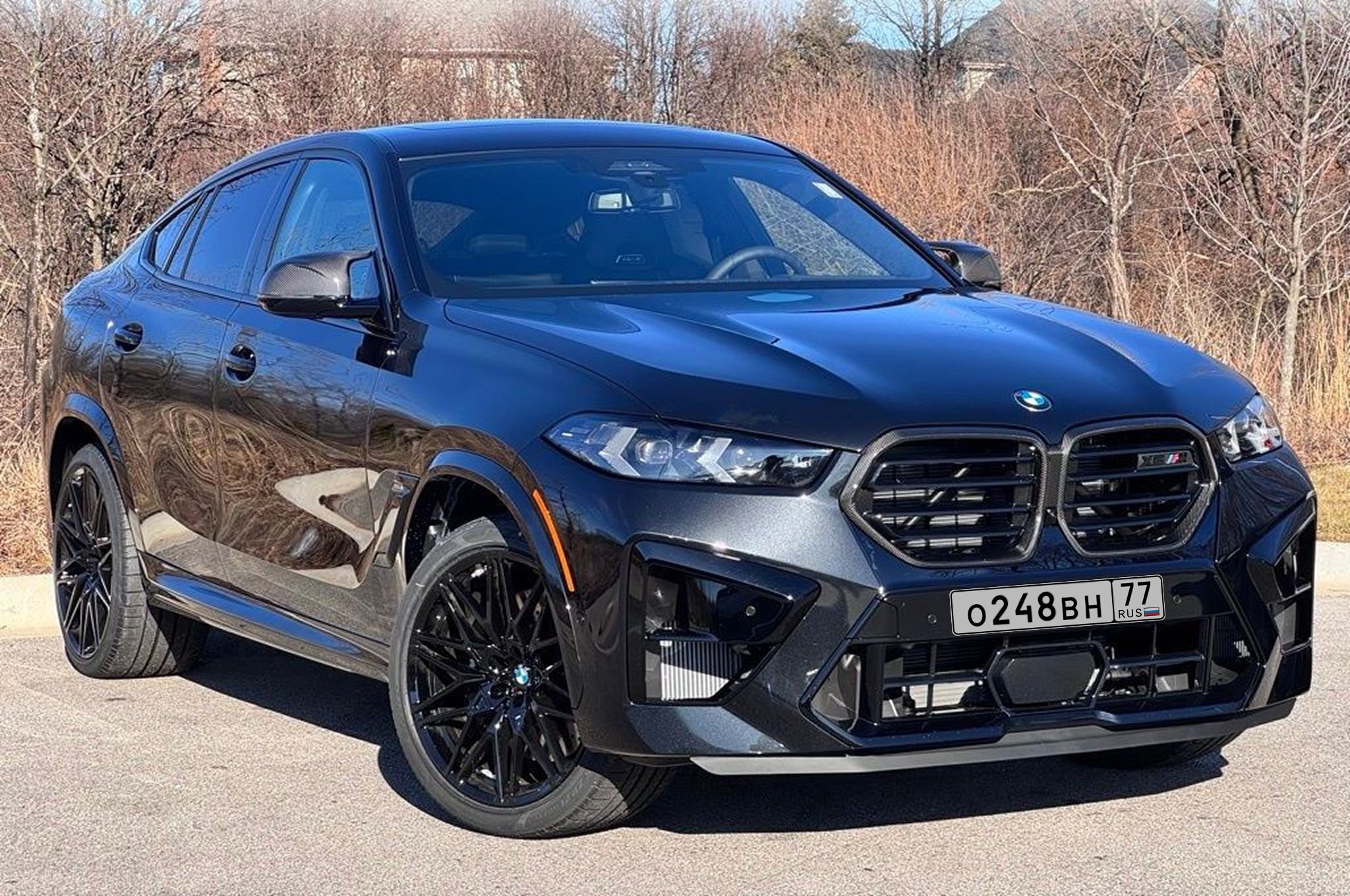 سيارة Mercedes SL مصورة على أرض حصوية وخلفها مبانٍ وسيارات أخرى