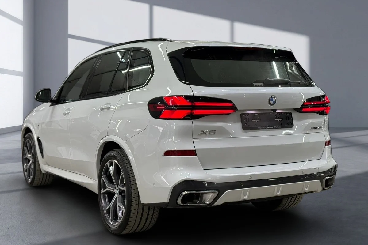 نفس سيارة BMW X5 بعد تغيير خلفية السيارة إلى صالة عرض مضيئة بواجهات زجاجية مع ظل ناعم تحت الإطارات
